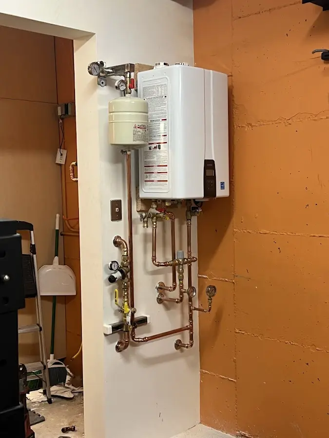 Plumbing technician inspecting water heater connections in Cobleskill